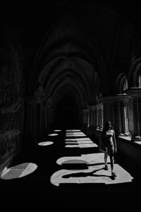 Shadow play around woman walking in porto cathedral.